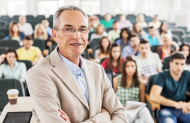 stock-photo-38640558-smiling-professor-in-the-classroom.jpg